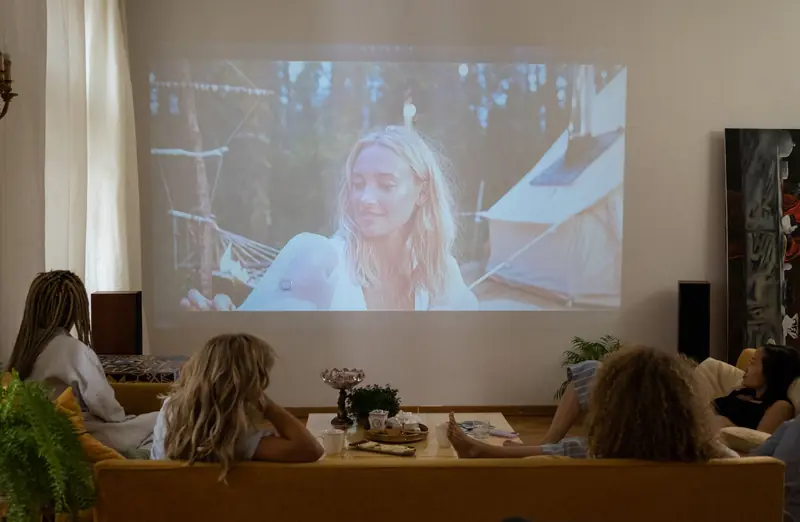Group of women enjoying a movie night at home, projected on a screen in a cozy living room