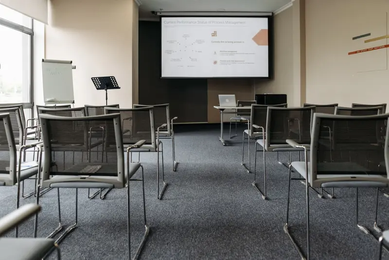 An empty conference room with chairs, a projector screen, and presentation setup
