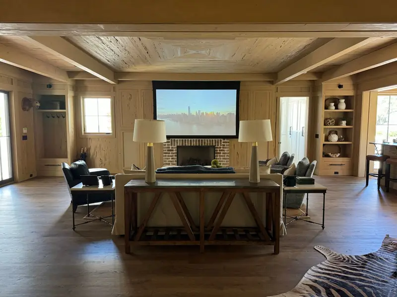 Stylish living room with projector screen, cozy seating, and wooden décor