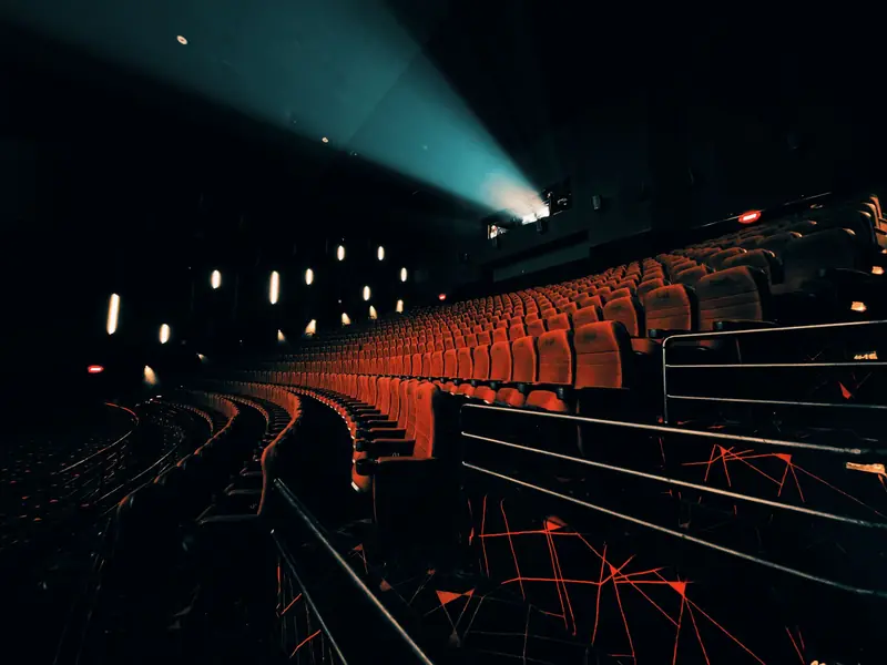 Dark, empty theater with dramatic seat lighting and projector beam