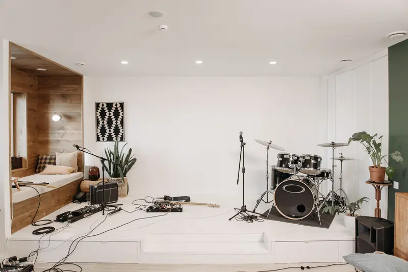 A modern music studio featuring a drum set, guitar, and cozy seating area for musicians