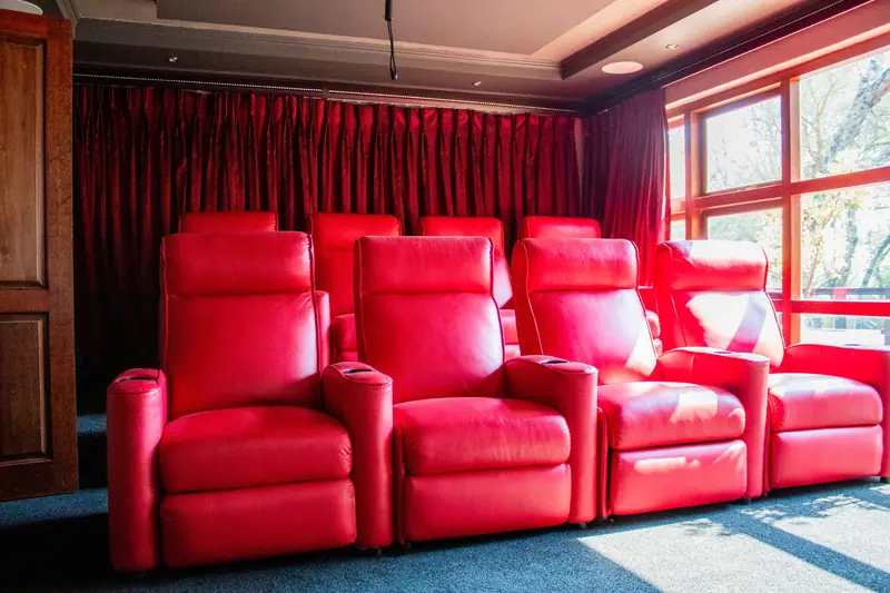 Elegant home theater featuring vibrant red leather reclining chairs and natural light