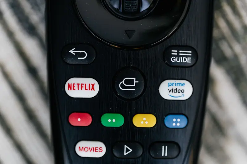 Detailed close-up image of a TV remote control with streaming service buttons