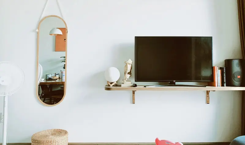 Stylish living room featuring a wall-mounted TV, a mirror, and modern decor on a white wall