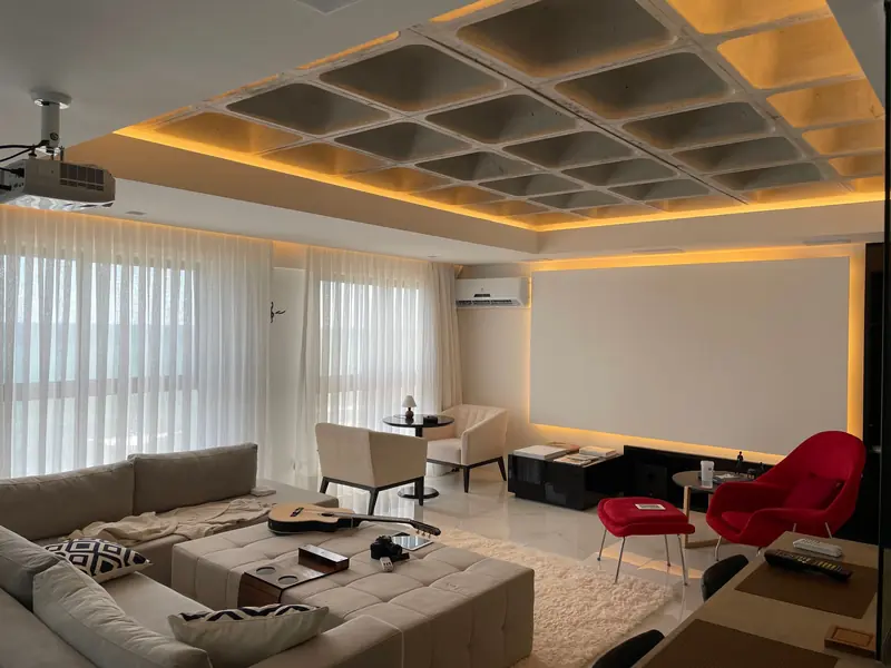 Spacious minimalist living room with natural light, featuring cozy seating and a ceiling projector